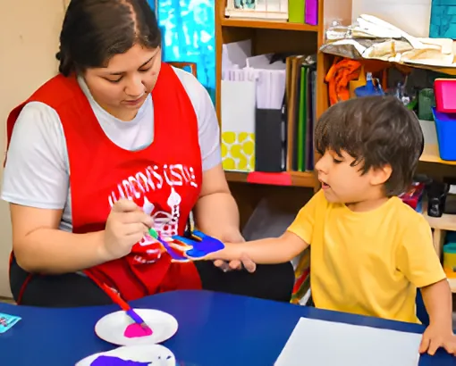 An Aladdin's Castle teacher in a red apron helping a boy with a painting project